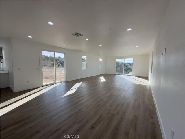 unfurnished living room with plenty of natural light and dark hardwood / wood-style flooring