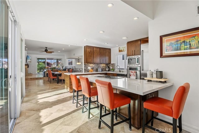 kitchen with appliances with stainless steel finishes, a kitchen bar, kitchen peninsula, and sink