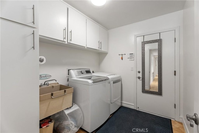 laundry area featuring cabinets, separate washer and dryer, sink, and dark tile patterned flooring