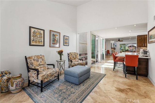 living area with ceiling fan and a towering ceiling