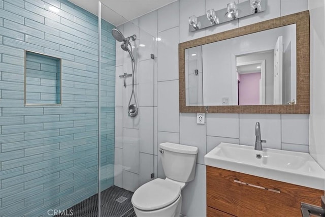 bathroom featuring vanity, a shower with shower door, tile walls, and toilet