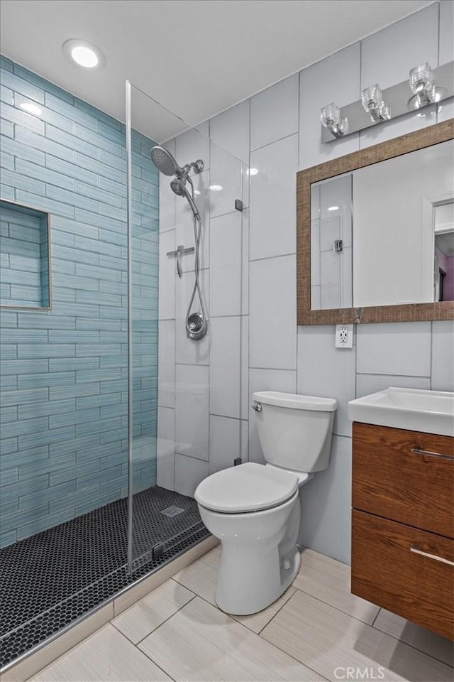 bathroom featuring vanity, a shower with shower door, and toilet