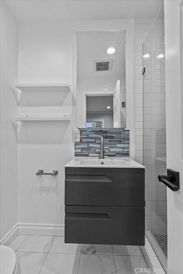 bathroom with vanity, tiled shower, decorative backsplash, and toilet