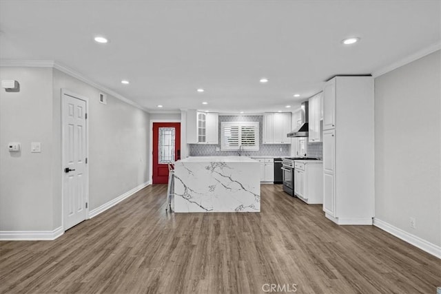 kitchen with a kitchen island, hardwood / wood-style floors, white cabinetry, backsplash, and stainless steel range