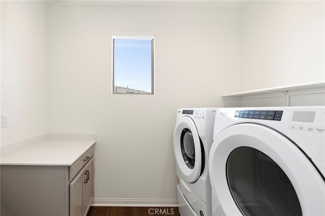 laundry room with dark hardwood / wood-style floors, washing machine and dryer, and cabinets