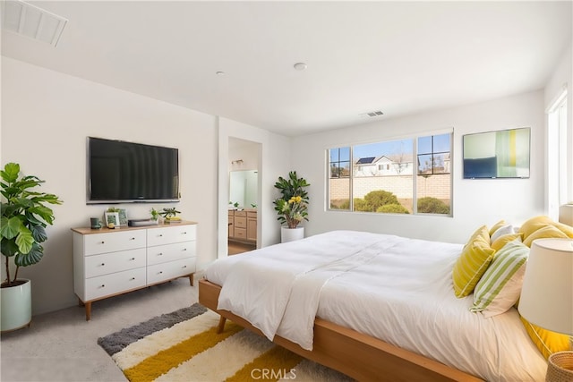 carpeted bedroom featuring ensuite bathroom and multiple windows