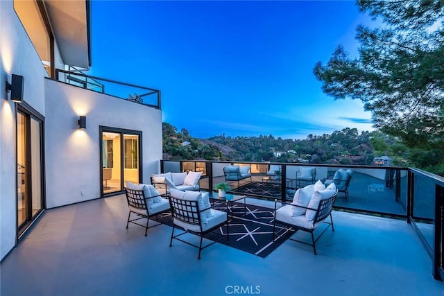 patio terrace at dusk with a balcony and an outdoor hangout area