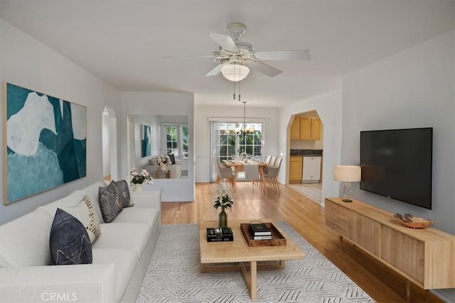 living room with ceiling fan with notable chandelier and light hardwood / wood-style floors