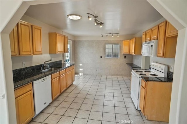 kitchen with light tile patterned flooring, white appliances, sink, and dark stone countertops