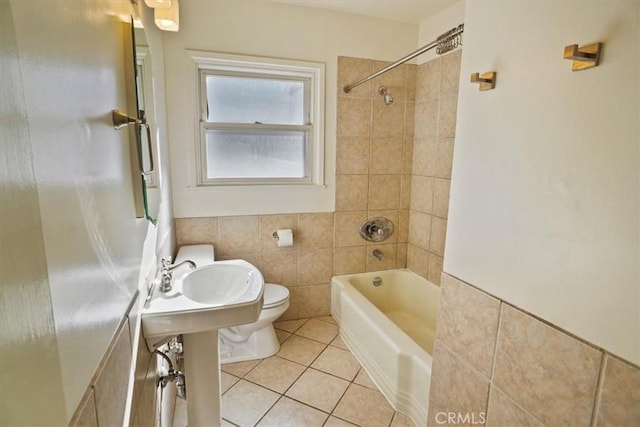 bathroom with tiled shower / bath, toilet, tile patterned flooring, and tile walls