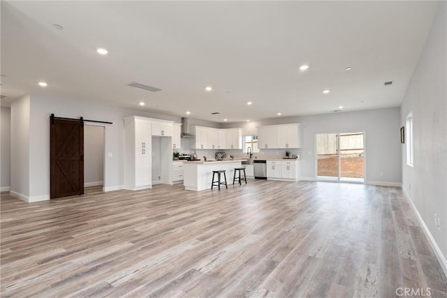 unfurnished living room featuring sink, a barn door, and light wood-type flooring