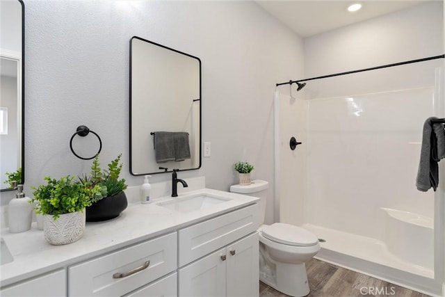 bathroom featuring vanity, hardwood / wood-style flooring, toilet, and walk in shower