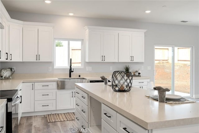 kitchen featuring electric stove, sink, white cabinetry, and a wealth of natural light