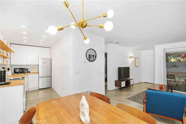 dining area featuring recessed lighting, concrete floors, and an inviting chandelier