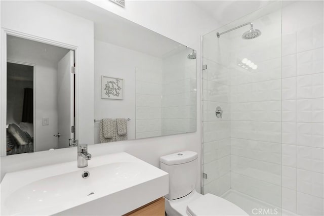 full bath featuring vanity, toilet, and a tile shower