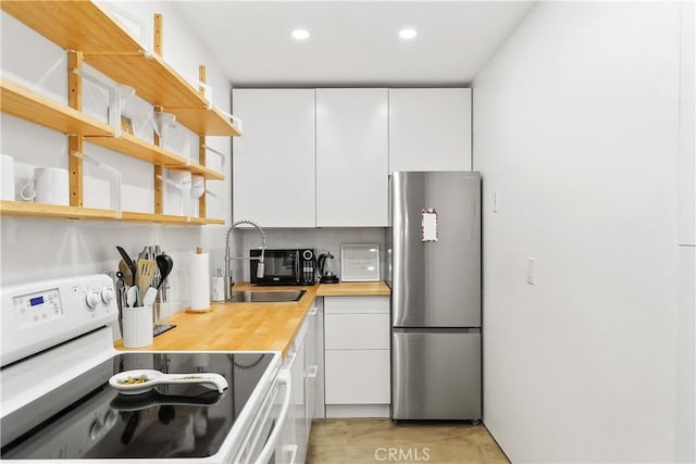 kitchen featuring a sink, freestanding refrigerator, white cabinetry, white electric range, and open shelves