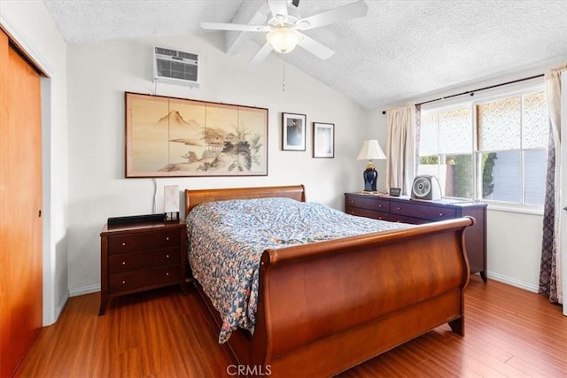 bedroom featuring hardwood / wood-style flooring, vaulted ceiling with beams, a wall mounted AC, and a textured ceiling