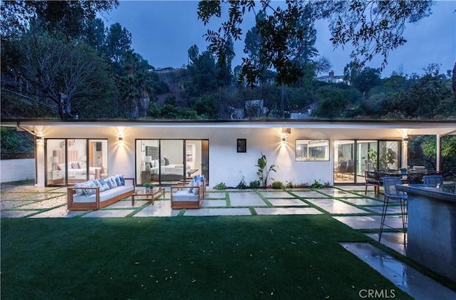 rear view of property with outdoor lounge area, a patio, and a lawn