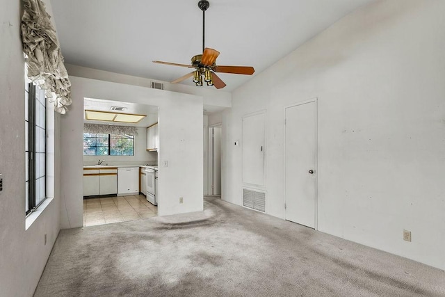 unfurnished living room with light carpet, sink, and ceiling fan