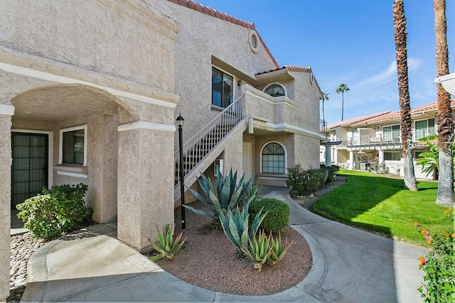 exterior space featuring a front lawn and a balcony