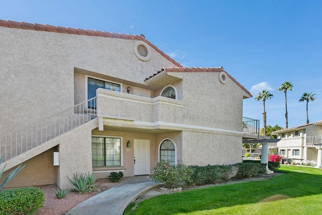 view of front of house featuring a balcony and a front yard