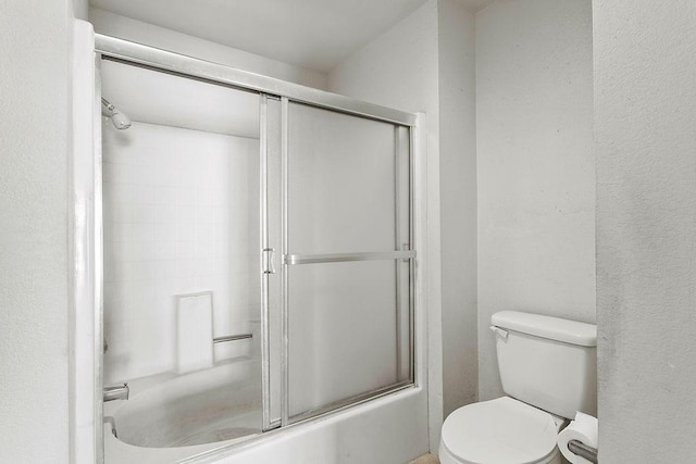 bathroom with shower / bath combination with glass door and toilet