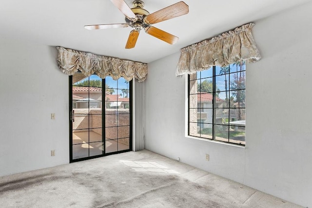 carpeted empty room with plenty of natural light and ceiling fan