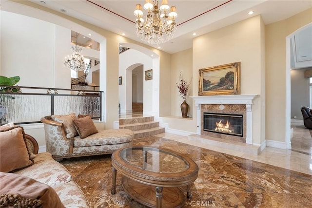 living area featuring a high end fireplace, arched walkways, marble finish floor, a notable chandelier, and recessed lighting