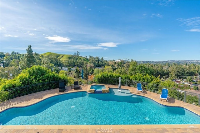 view of swimming pool featuring a patio, fence, and a pool with connected hot tub