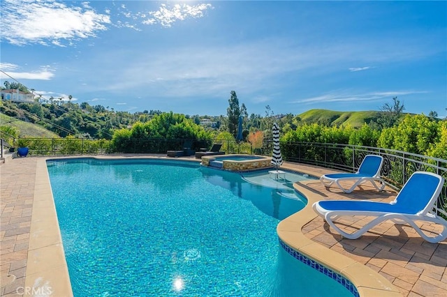 view of pool with a patio, a pool with connected hot tub, and fence
