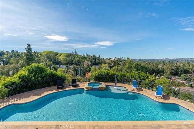 view of swimming pool with a patio, a pool with connected hot tub, and fence