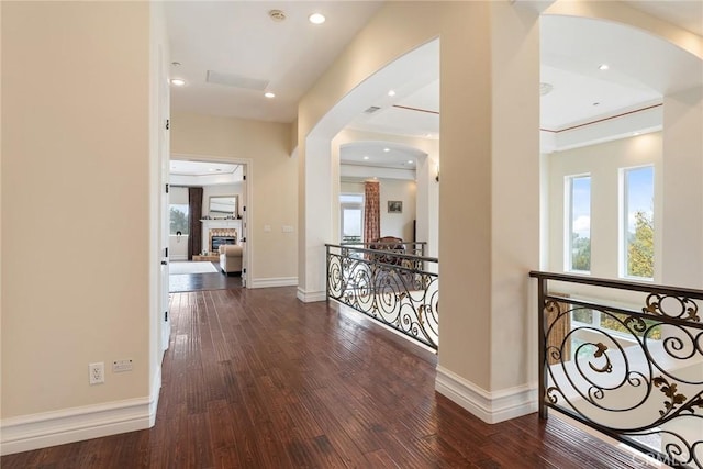 hall featuring arched walkways, baseboards, an upstairs landing, and hardwood / wood-style flooring