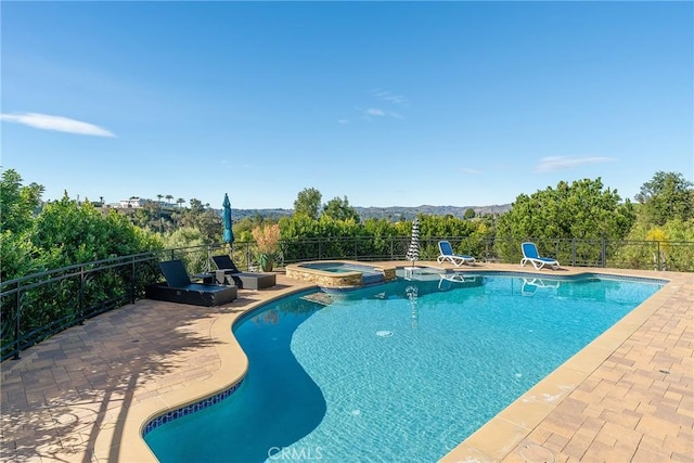 view of swimming pool with fence, a patio, and a pool with connected hot tub