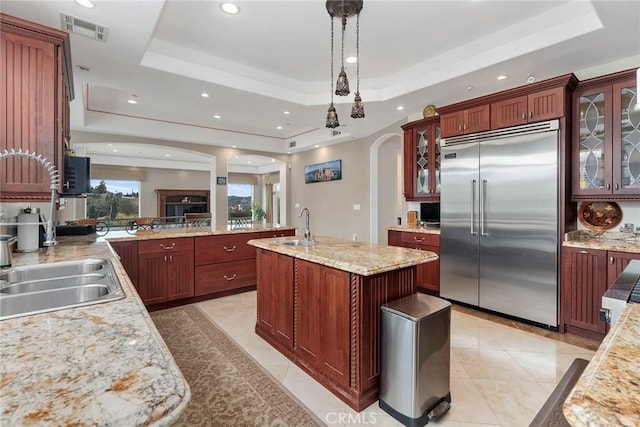 kitchen featuring a tray ceiling, a sink, and stainless steel built in refrigerator