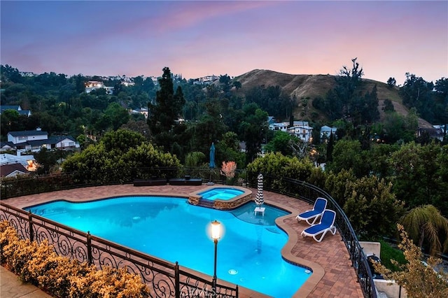 view of swimming pool featuring fence, a patio, a water slide, a mountain view, and a pool with connected hot tub