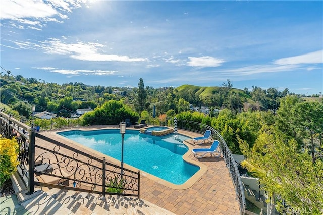 view of swimming pool featuring a patio area, a pool with connected hot tub, and fence