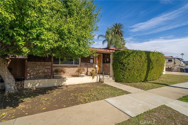 obstructed view of property featuring stone siding and fence