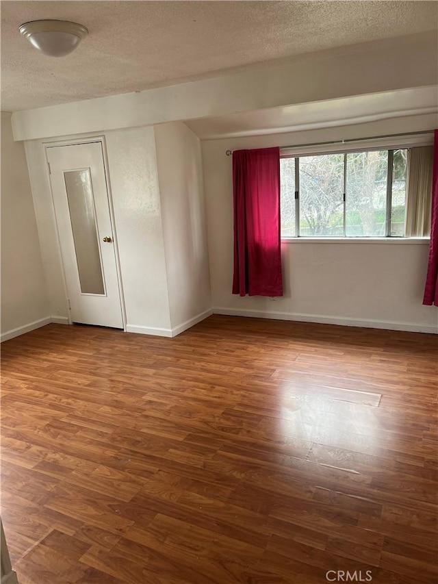 empty room with hardwood / wood-style floors and a textured ceiling