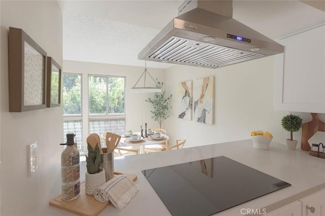 kitchen with white cabinetry, island range hood, a textured ceiling, black electric cooktop, and pendant lighting