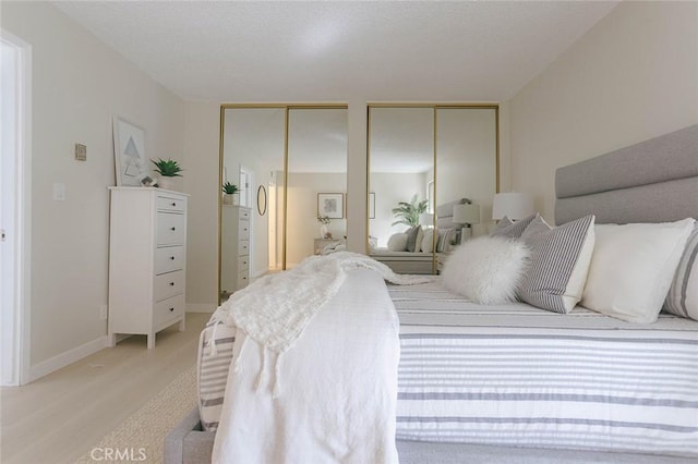 bedroom featuring multiple closets and light wood-type flooring