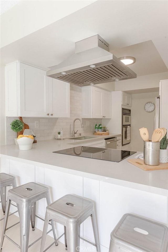 kitchen with island range hood, white cabinets, and kitchen peninsula