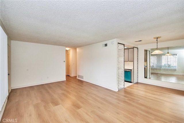 unfurnished living room with light wood-type flooring and a textured ceiling