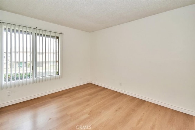 unfurnished room featuring light hardwood / wood-style flooring and a textured ceiling