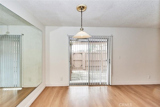 unfurnished dining area with a textured ceiling and hardwood / wood-style flooring