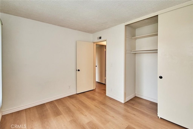 unfurnished bedroom with light hardwood / wood-style flooring, a closet, and a textured ceiling