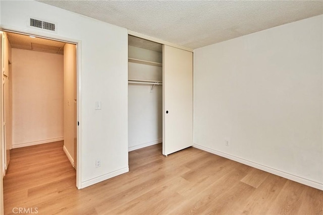 unfurnished bedroom featuring light wood-type flooring, a closet, and a textured ceiling