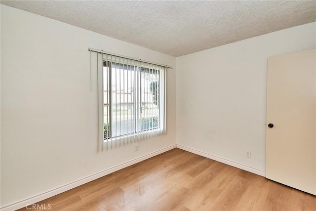 empty room with light hardwood / wood-style flooring and a textured ceiling