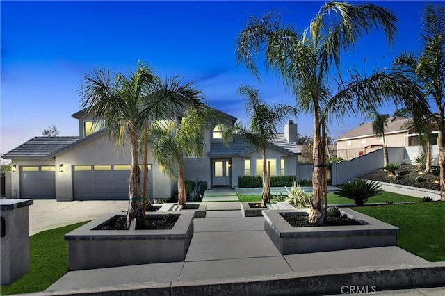 view of front of property with a garage, a fire pit, and a lawn