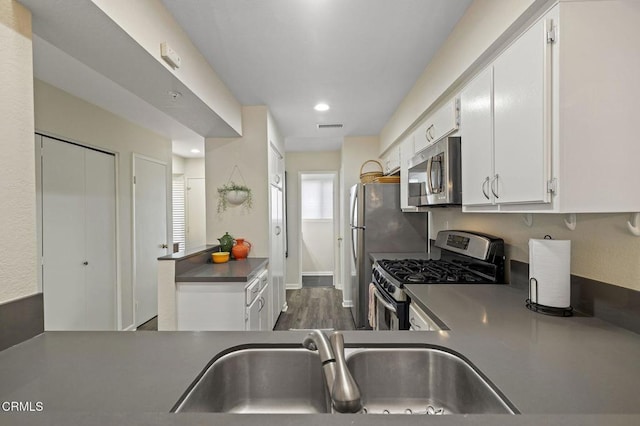 kitchen with stainless steel appliances, white cabinetry, sink, and dark hardwood / wood-style floors