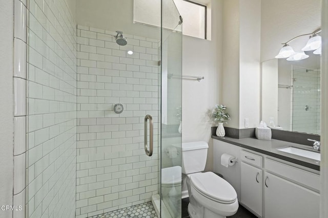 bathroom featuring vanity, toilet, and a shower with door